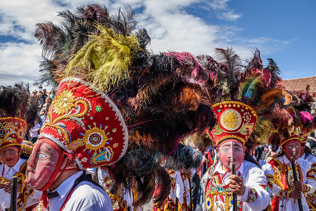 Cusco, ein kulturelles Fest, Menschen in traditionellen bunten Kostümen mit Masken und Hüten mit Federn.