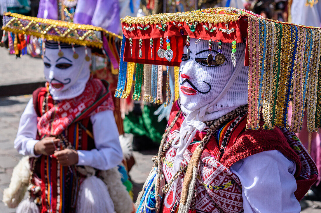 Cusco, ein kulturelles Fest, Menschen in traditionellen bunten Kostümen mit Masken und Hüten, bunte Luftschlangen.