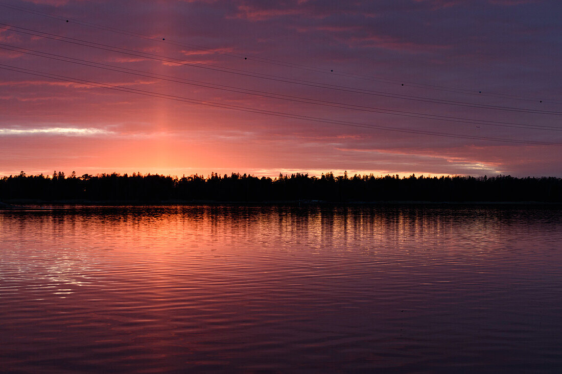 The coastline of islands near Helsinki, at sunset, a red glow in the sky. 