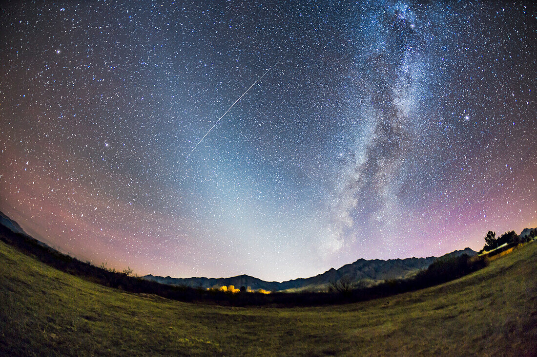 Das Zodiakallicht am späten Herbstabendhimmel von Arizona, mit Blick auf die Chiricahua Mountains bei Portal, AZ. Das Zodiakallicht erhebt sich vom Horizont bis zu dem Winkel, der der Ekliptik folgt. Die sommerliche Milchstraße, die im Südwesten untergeht, erstreckt sich vom Horizont nach rechts oben und verläuft durch die Mitte der Sterne des Sommerdreiecks. Ein Satellit streift das Zodiakallicht in einer auffälligen Bahn. Ich habe dies vom Feld bei Quailway Cottage aus aufgenommen.