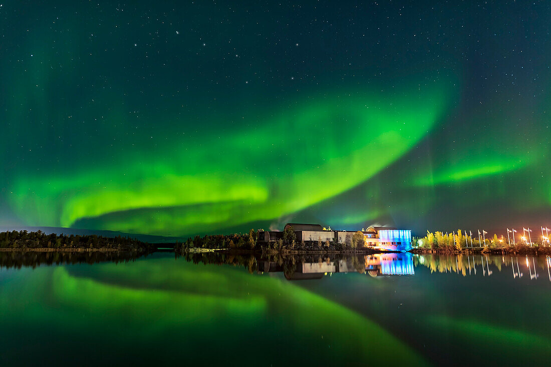 Aurora reflected in the calm waters of Frame Lake this evening and arching over the Prince of Wales Museum in Yellowknife, NWT, on Sept 5, 2019. The Museum exterior is lit by rippling coloured LED lights that mimic the aurora. The Big Dipper and Ursa Major are above the aurora. The arc of the Lights was brighter earlier on this evening but had faded by the time I got set, but came back somewhat, as I shot here. I shot this from Somba K’e Park.