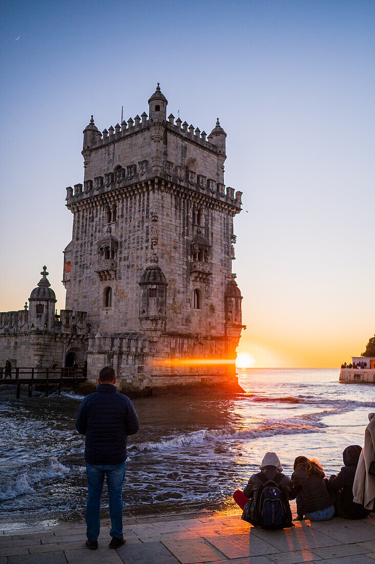 People enjoy a beautiful sunset from Belem Tower or Tower of St Vincent on the bank of the Tagus River, Lisbon, Portugal