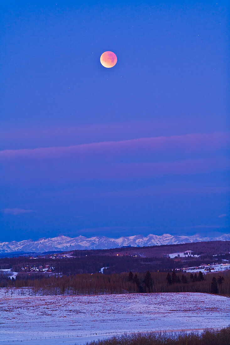 Dies ist die totale Mondfinsternis am 10. Dezember 2011, aufgenommen vom Gelände des Rothney Astrophysical Observatory in der Nähe von Priddis, Alberta, mit Blick nach Westen zu den Rocky Mountains. Es handelt sich um eine 2-Sekunden-Belichtung bei ISO 800 mit der Canon 5DMkII und dem Canon 200mm-Objektiv bei f/4. Die Aufnahme entstand gegen Ende der Totalität um 7:48 Uhr Ortszeit.