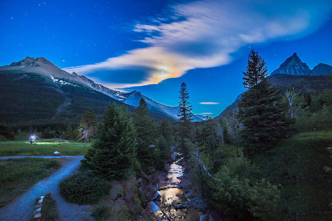 A nightscape photographer from one of my workshops, shooting in the moonlight at Red Rock Canyon, in Waterton Lakes National Park, Alberta. Clouds partly obscure the gibbous Moon but add a colourful iridescent corona around the Moon, which is reflected in the Red Rock Canyon Creek. This is an HDR stack of 5 exposures with the 14mm lens and Canon 6D, to preserve detail in the bright clouds and the disk of the Moon, and in the dark shadows.