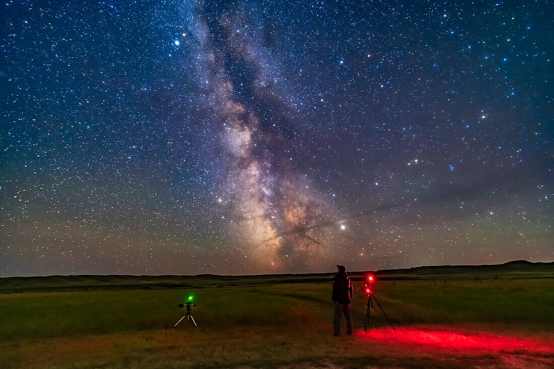 A selfie of me shooting time-lapses and tracked Milky Way images at the 76 Ranch Corral site at Grasslands National Park, August 27, 2019. Taken for use as a book cover. High cloud and a dark aircraft contrail drifting through added the star glows and the dark streak. Jupiter, at right, and Saturn, at left, flank the Milky Way. Altair is the bright star at top.