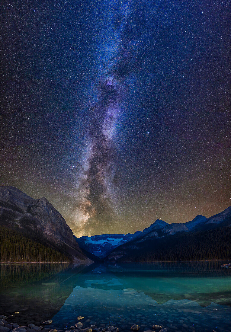 Galaxie und Gletscher! Dies ist ein vertikales Panorama der Milchstraßengalaxie über dem Lake Louise und dem Victoria-Gletscher im Banff National Park, Alberta. Die Sterne des Sommerdreiecks Vega, Deneb und Altair befinden sich in der Mitte. Die Scutum-Sternwolke befindet sich direkt über dem Victoria-Gletscher und geht dort unter. Die dunklen Bahnen aus interstellarem Staub stardust! schlängeln sich zwischen den hellen Sternwolken der Milchstraße.