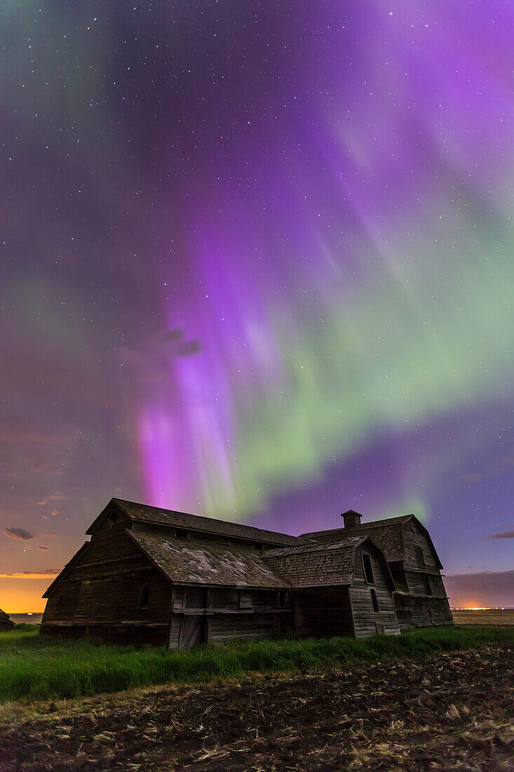 An all-sky aurora with green and purple curtains, the night of June 7-8, 2014, starting up about 12:30 and going until dawn. This shot was near its peak, from the old barn site near home in southern Alberta. Foreground illumination is from the aurora and ambient sky -- the Moon had set. The Big Dipper is above the Barn. The purple colour is from blue scatttered sunlight hitting the red tops of the auroral curtains. This was with the 16-35mm lens at f/3.2 for 20 seconds at ISO 1600 with the Canon 6D.