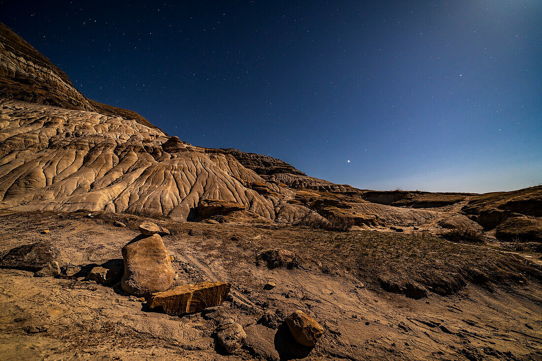 Jupiter in Libra is rising over the moonlit Badlands on Highway 10 east of Drumheller, Alberta. Light from the waxing gibbous Moon off frame to the upper right provides the illumination on April 26, 2018.