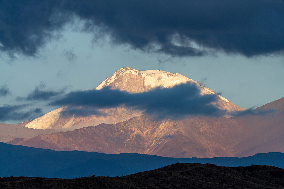 Sonnenaufgangslicht beleuchtet den schneebedeckten Vulkan Tupungato in den Anden in der Provinz Mendoza, Argentinien.