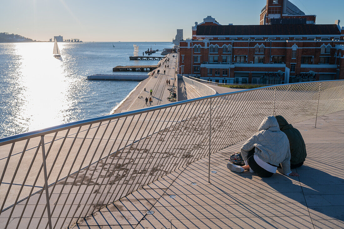 People on MAAT (Museum of Art, Architecture and Technology) roof, designed by the British architect Amanda Levete. View of Ponte 25 de Abril bridge. Belem, Lisbon, Portugal