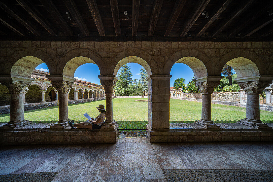 A woman reading in the cloister of the Abbey of Saint-Michel de Cuxa, France