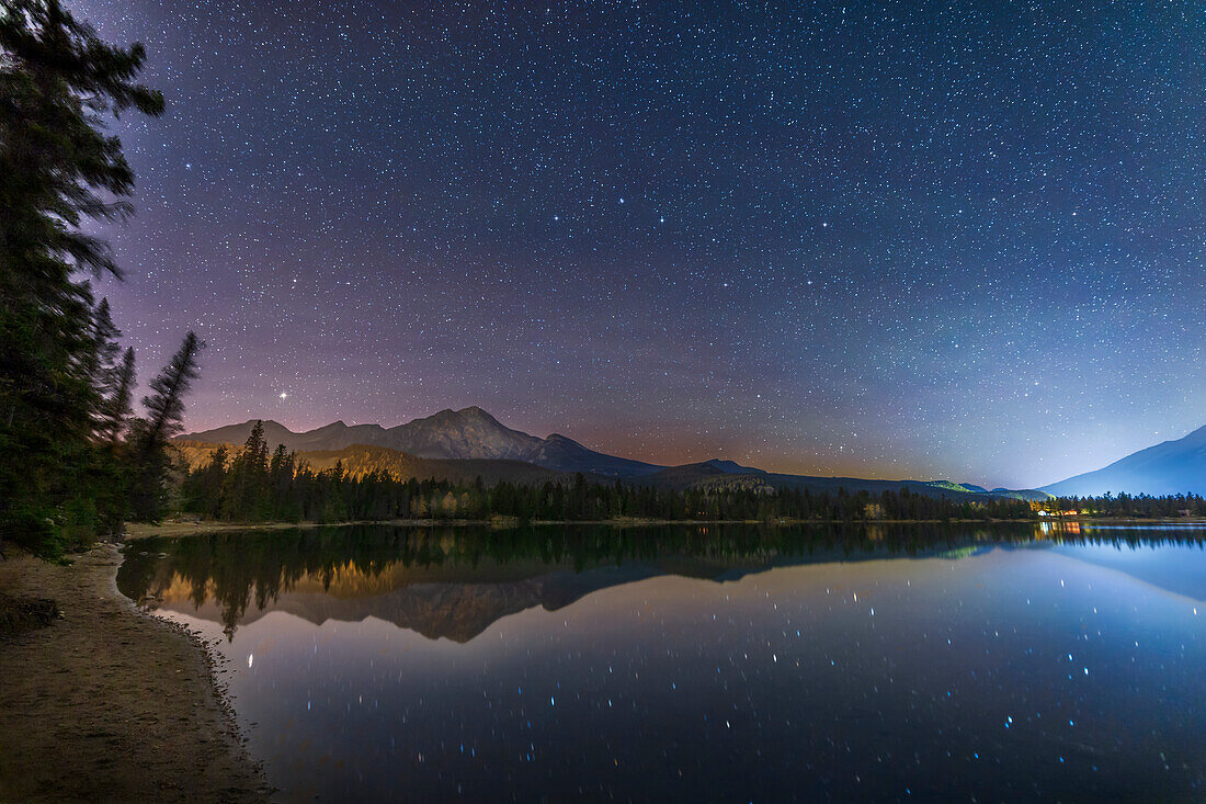 The constellation of Ursa Major, the Great Bear, and the asterism of the Big Dipper low in the north over Lake Edith in Jasper National Park, on a clear autumn night. Arcturus is at left setting over Pyramid Mountain.