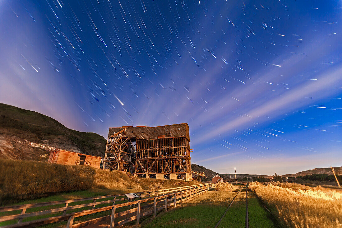 The old Atlas Coal Mine near East Coulee, Alberta, now a museum and tourist attraction. This is a composite of 20 x 1 minute exposures with the Canon 5D MkII and 16-35mm lens at 16mm and f/2.8, and ISO 1250. Taken June 27, 2013. While the Moon was up it was in some cloud and most of the illumination of the foreground comes from a sodium vapour light just off camera at right. Images stacked with StarCircleAcademy's Advanced Stacker Actions, Comet Streaks option.