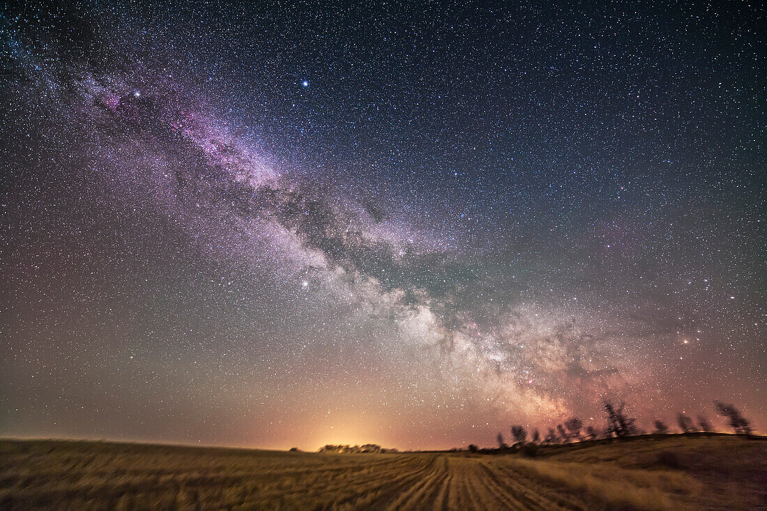 The summer Milky Way rising late on a spring night over a fallow wheatfield in spring, 2013. Taken from home, May 6, 2013, with the Canon 5D MkII and Samyang 14mm lens at f/2.8 for a stack of 5 x 2.5 minute exposures at ISO 1600, all tracked on the iOptron Sky-Tracker. The ground is from one exposure. Taken from a latitude of +50° so Scorpius at right and Sagittarius right of centre are skimming the southern horizon. Taken from southern Alberta, Canada.