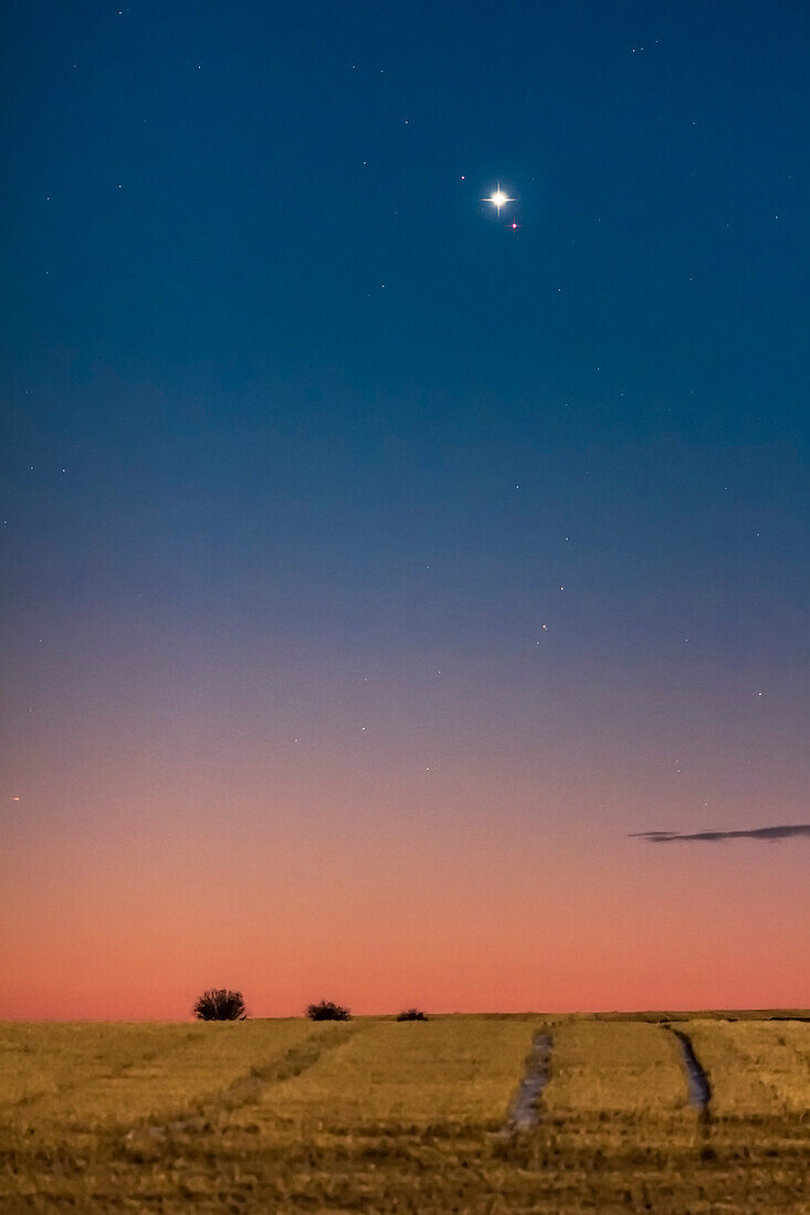 Venus und Mars in enger Konjunktion am Morgenhimmel am 5. Oktober 2017. Venus ist das hellste Objekt; Mars befindet sich darunter; der Stern über der Venus ist Sigma Leonis (4. Größenklasse). Der Vordergrund wird vom Licht des untergehenden Vollmonds im Westen beleuchtet.