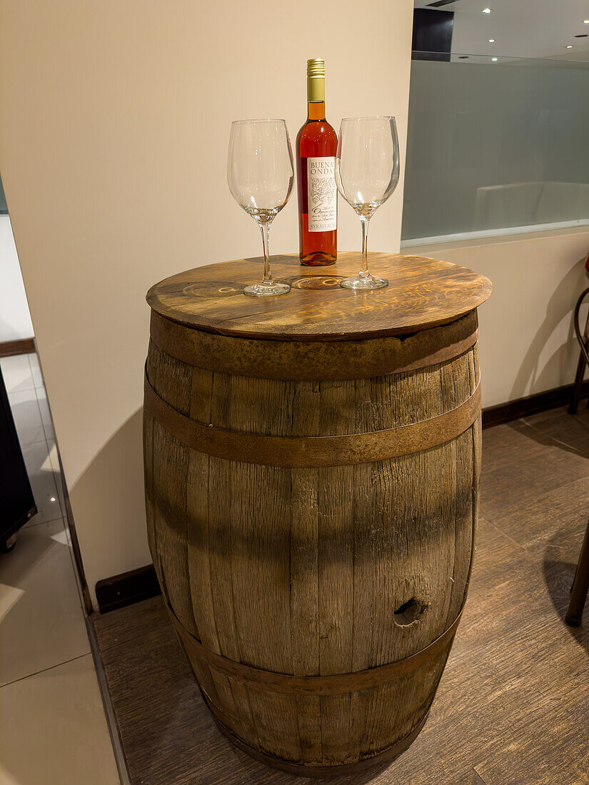 A bottle of wine and wine glasses on an old wine barrel as decor in a hotel in San Juan, Argentina.