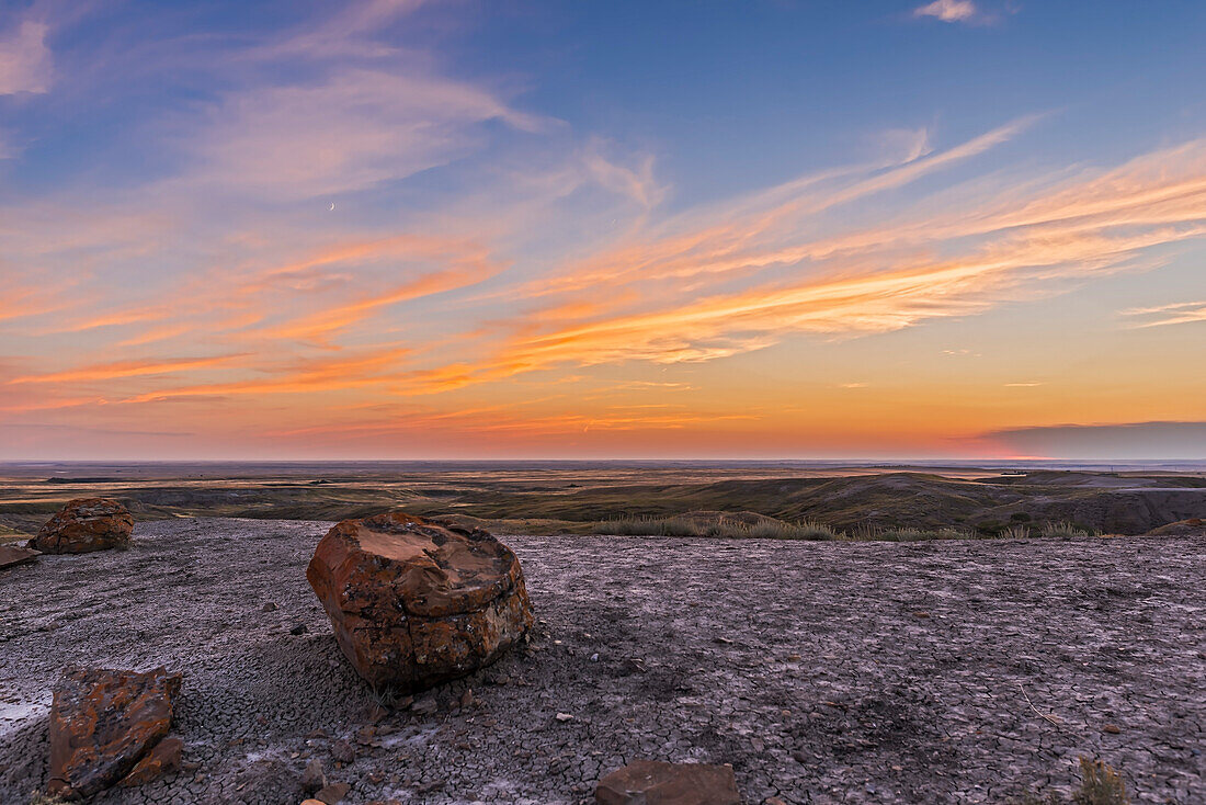 Die zunehmende 3 Tage alte Mondsichel am Abendhimmel über der Red Rock Coulee Natural Area im Südosten Albertas. Die Sonne ist an dem Punkt am Horizont ganz rechts untergegangen, am Rande der dunklen Wolke aus Waldbrandrauch.