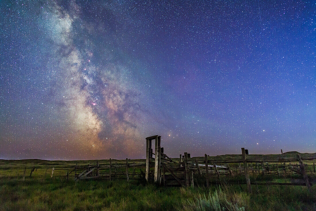 Mars (unten) und Saturn in Konjunktion rechts, und die Milchstraße links, in tiefblauer Dämmerung, bevor der Himmel richtig dunkel wurde, über dem alten Korral der 76 Ranch, im Grasslands National Park, Saskatchewan, 27./28. August 2014. Antares und Scorpius sind direkt hinter dem Tor der Ranch rechts, Sagittarius ist links in der Milchstraße. Die offenen Sternhaufen M6 und M7 sind links zu sehen.