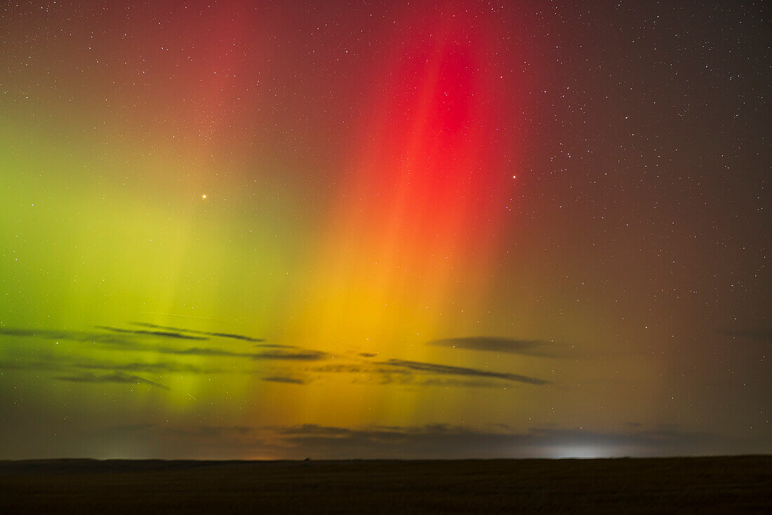 Eine Illustration eines roten Polarlichtvorhangs, der sich mit dem grünen Polarlichtbogen vermischt und einen gelb-orangenen Bereich im Polarlicht dieser Nacht bildet. Dieses Bild wurde am 26. September 2022 von zu Hause in Alberta aufgenommen. Es umrahmt die Sterne des aufgehenden Taurus mit dem hellen Mars links und dem Hyaden-Sternhaufen rechts.