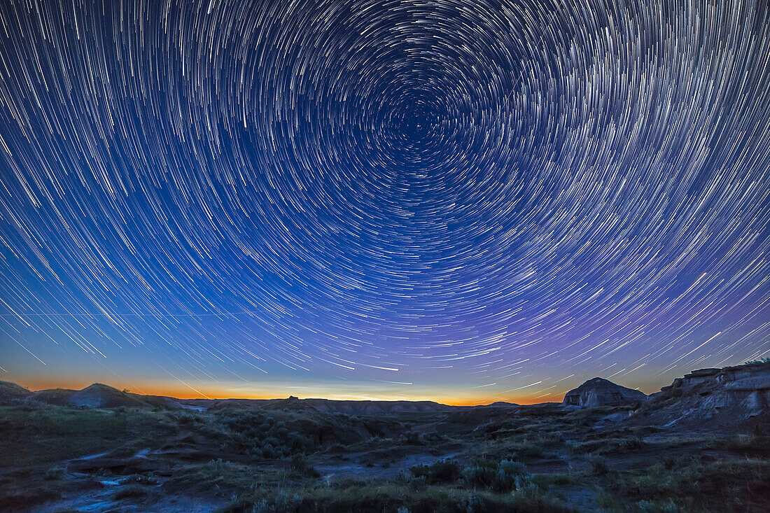 Sommersonnenwende-Dämmerung und zirkumpolare Sternenspuren über den Badlands des Dinosaur Provincial Park, Alberta. Einige helle, nachtleuchtende Wolken sind tief am nördlichen Horizont zu sehen. Ich habe dies am 15. Juni 2015 als Teil einer Aufnahme für ein Video-Tutorial über Sternenspuren als Beispielbild aufgenommen.