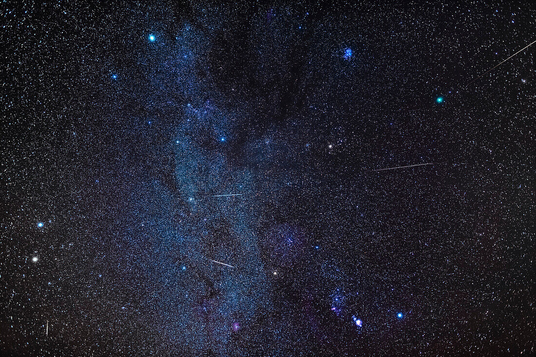 A composite of several exposures to stack images of five Geminid meteors into a wide view of the winter sky with Comet Wirtanen at upper right in Taurus, taken on December 12, 2018. The meteors are shooting away from the radiant point in Gemini near the bluish-white star Castor at left. The Milky Way runs vertically through the frame from Auriga at top to past Orion at bottom.