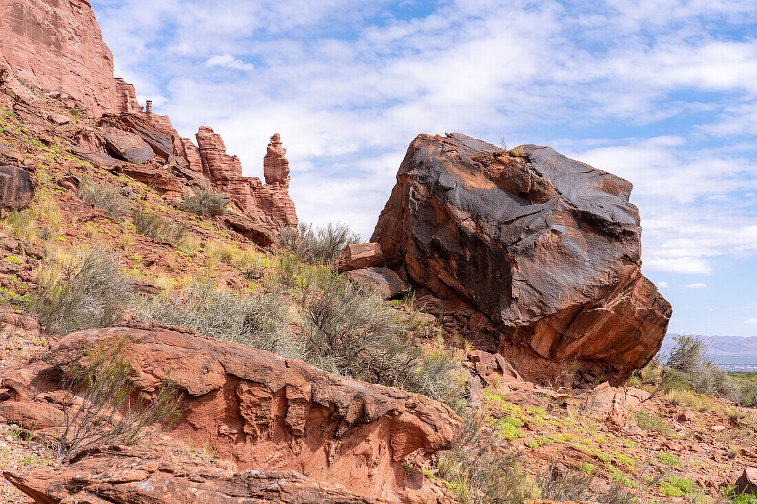 A large boulder with rock art in front of a sandstone rock spire at the Puerta del Cañon in Talampaya National Park, Argentina.