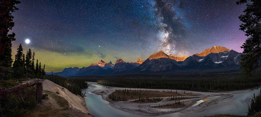 A panorama of the glacier-fed Athabasca River and peaks around Mount Fryatt in Jasper National Park, as the Milky Way is setting and the waning gibbous Moon rising, lighting the peaks of the Continental DIvide with lunar alpenglow. Mount Fryatt is at centre, while to the right is Mount Geraldine, and to the left are Brussels Peak and Mount Christie. Jasper is one of the world's largest Dark Sky Preserves.