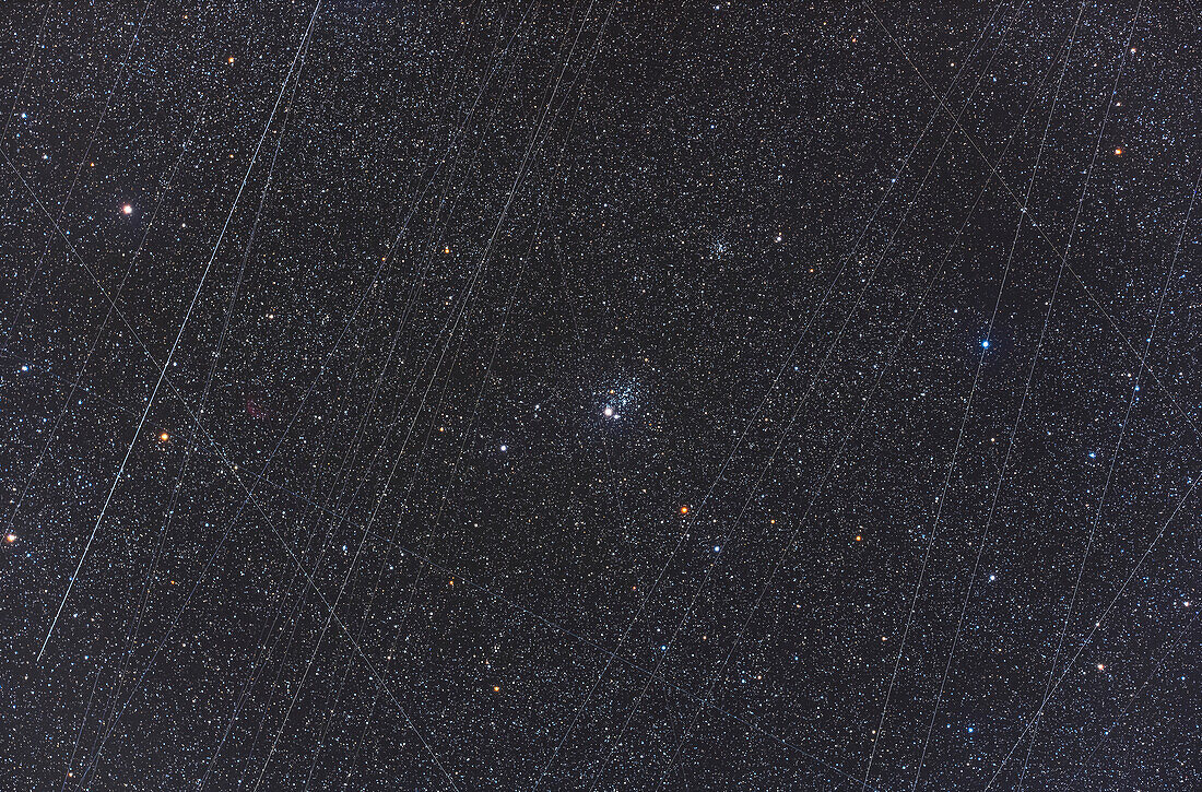 This is NGC 457, the ET or Owl Cluster in Cassiopeia, in a stack of images showing the total number of satellite trails recorded over the 36 minutes of total expposure time this night. By coincidence, the trails frame the main subject, but the number of satellites now above us make it nearly impossible to take a long exposure image, certainly at the start or end of a night, without recording at least one satellite trail, if not more, per image. Some of the parallel streaks could be Starlink satellites.