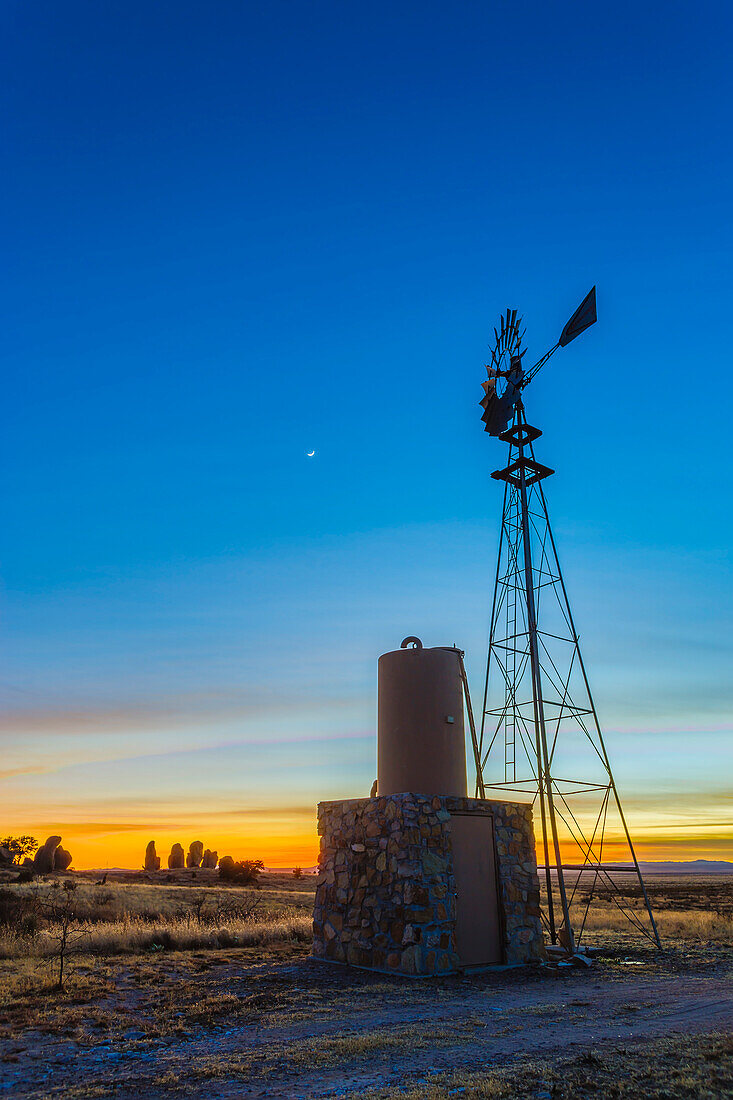 Die zunehmende Mondsichel am Dämmerungshimmel hinter einer Windmühlen-Wasserpumpe im City of Rocks State Park, New Mexico, Heiligabend, 24. Dezember 2014. Dies ist ein HDR-Stapel mit hohem Dynamikbereich aus 7 Belichtungen in 2/3-Stufen-Intervallen mit der Canon 6D und dem 24-mm-Objektiv.