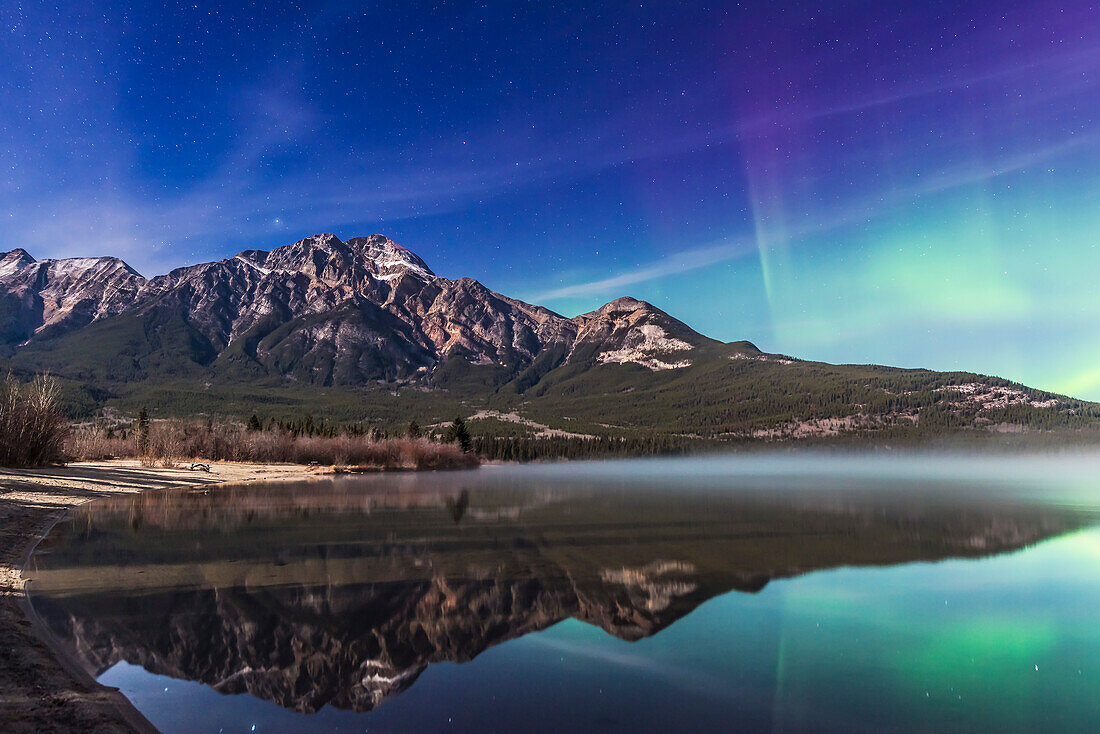 An aurora display appears to the right of Pyramid Mountain and over Pyramid Lake, in Jasper National Park, Alberta on Oct 24/25, 2015. This is one frame from a 600-frame time-lapse sequence. Exposure was 15 seconds at f/4 and ISO 800 in the bright moonlight, with the Nikon D750 and 24mm Sigma lens.
