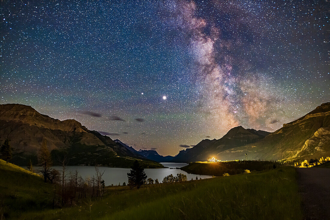 Der galaktische Kernbereich der Milchstraße über dem Waterton Lakes National Park, Alberta, mit der Paarung der Riesenplaneten im Sommer 2020. Jupiter ist das helle Objekt in der Mitte, der Saturn links (östlich) von Jupiter ist schwächer. Im Jahr 2020 standen die beiden Planeten am Sommerhimmel dicht beieinander. Schütze ist rechts zu sehen. Das Prince of Wales Hotel ist die helle Lichtquelle. Dies war am 13. und 14. Juli 2020.