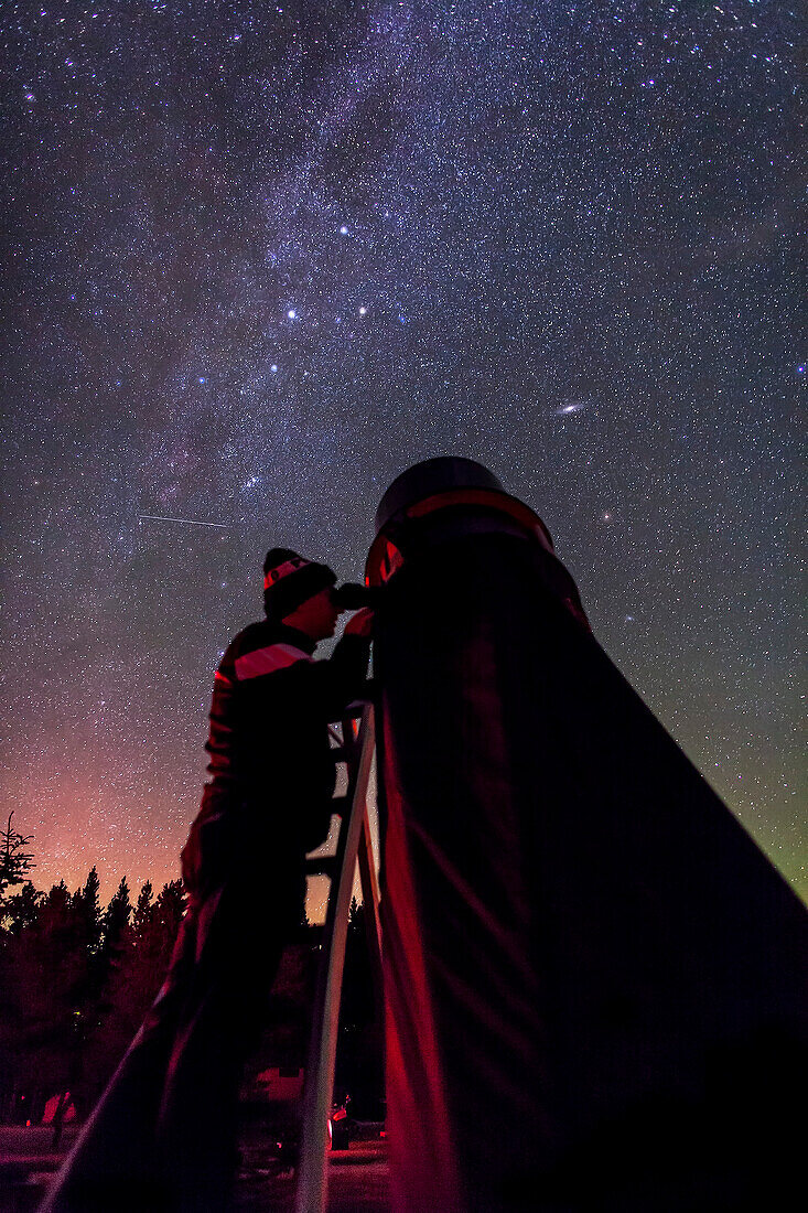 Der Astronom Vance Petriew am Okular seines 20-Zoll-Dobson-Spiegelteleskops bei der Saskatchewan Summer Star Party 2012 in Cypress Hills, SK. Dies ist eine Einzelbelichtung von 20 Sekunden mit der Canon 5DMkII bei ISO 4000 und einem 24-mm-Objektiv der Canon L-Serie bei f/2. Ein schwaches Polarlicht fügt die Horizontfarben hinzu. Das Foto wurde anlässlich der zweiten Rückkehr des Kometen Petriew 185/P seit seiner Entdeckung 11 Jahre zuvor im Jahr 2001 an genau diesem Ort aufgenommen.
