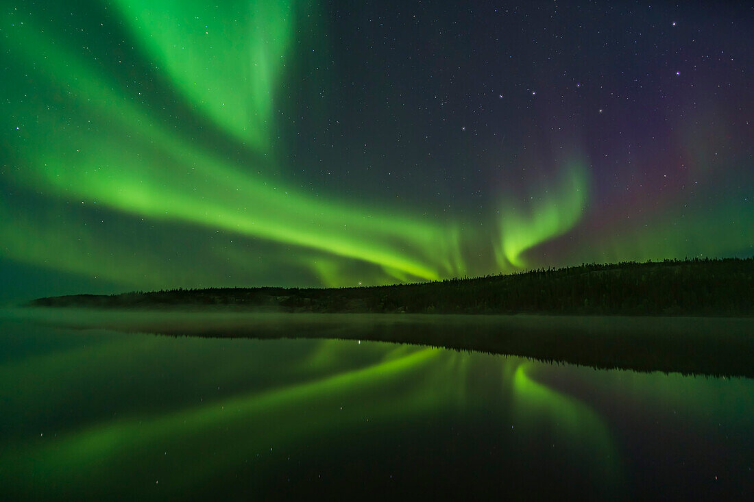 Reflections of the Northern Lights in the calm and misty waters of Madeline Lake on the Ingraham Trail near Yellowknife, NWT on Sept 7, 2019. This is one of a series of “reflection” images. The Big Dipper is at right. Arcturus is just setting over the ridge and is reflected in the water.