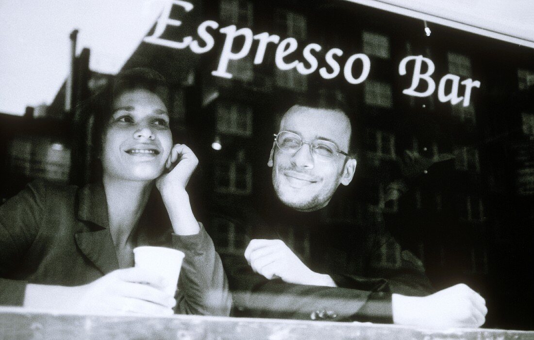Man and woman through the window of an espresso bar