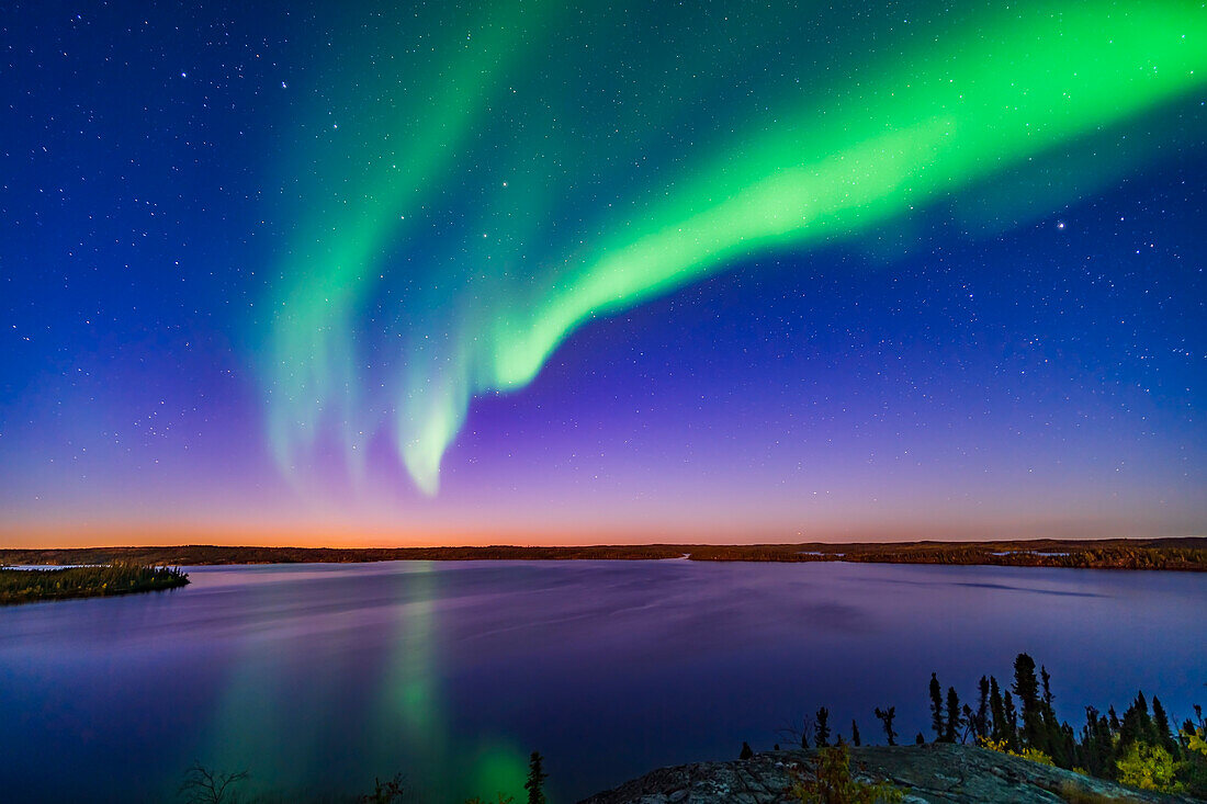 An arc of Northern Lights appears in the evening twilight over Prelude Lake near Yellowknife, NWT, on September 9, 2019. The Big Dipper is at left. Capella is at right.