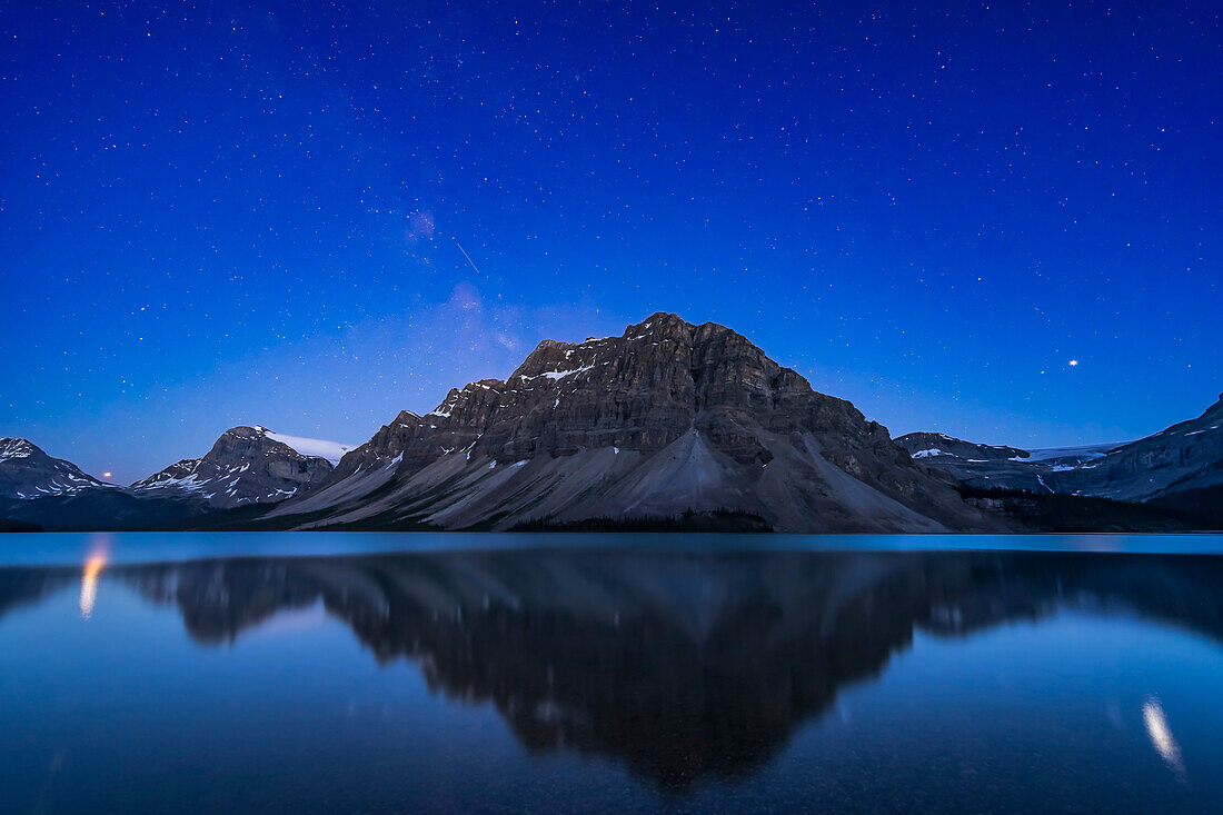 Bright planets Mars (reddish at left) and Jupiter (right, over Bow Glacier) over Bow Lake, in Banff, Alberta, and reflecting in the water in glitter paths on the lake.