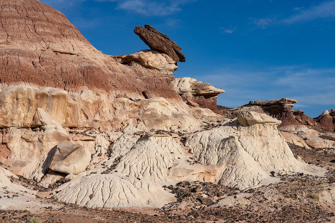 Ein Sandsteinkappenfelsen auf einem Lehm-Hoodoo in den Bentonit-Hügeln der Caineville-Wüste bei Hanksville, Utah.