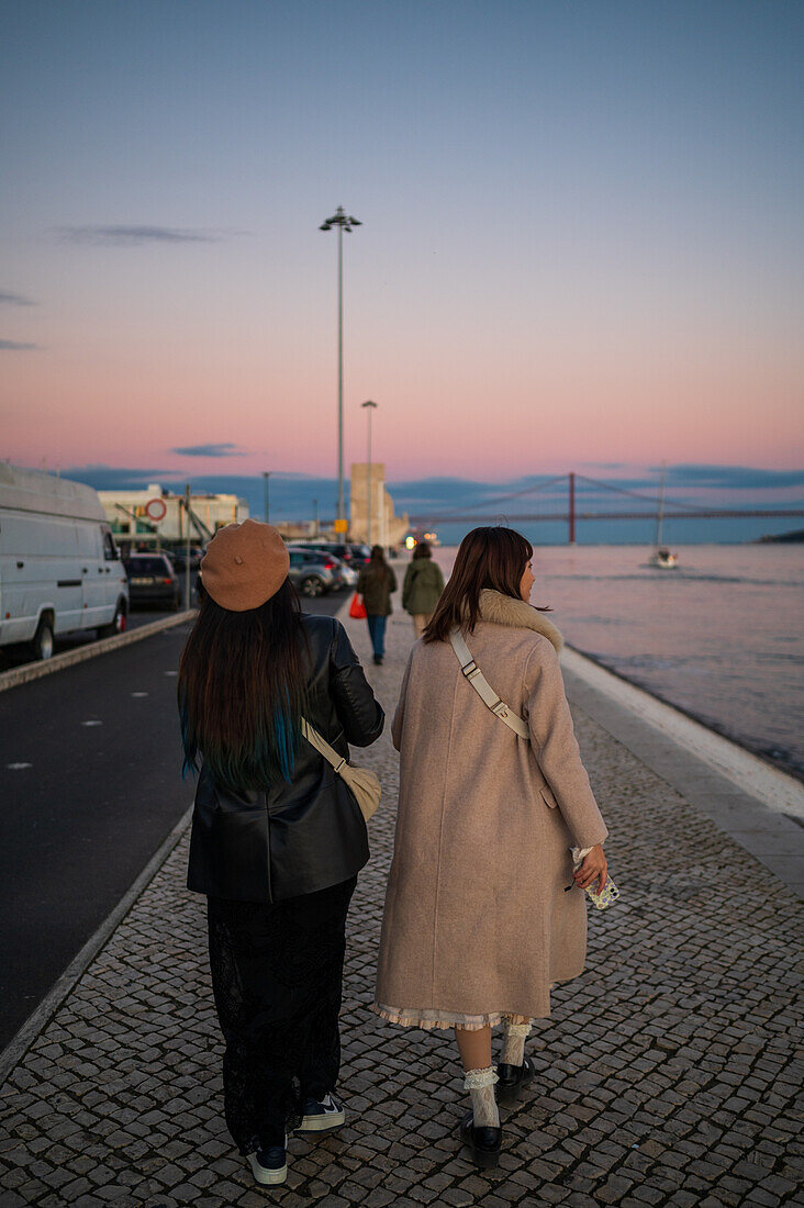 People enjoying the sunset in Belem promenade by Tagus River, Lisbon, Portugal