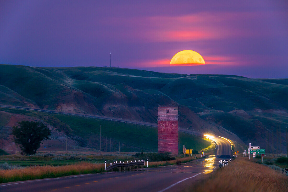 The Full Moon rise of August 11, 2022 over the old grain elevator on Highway 10 at Dorothy, Alberta, in the Badlands of the Red Deer River valley. This was dubbed a "supermoon" and the "Sturgeon Moon" in the popular media. It just happened to rise at a location that placed it right down the south-east facing highway in the valley.