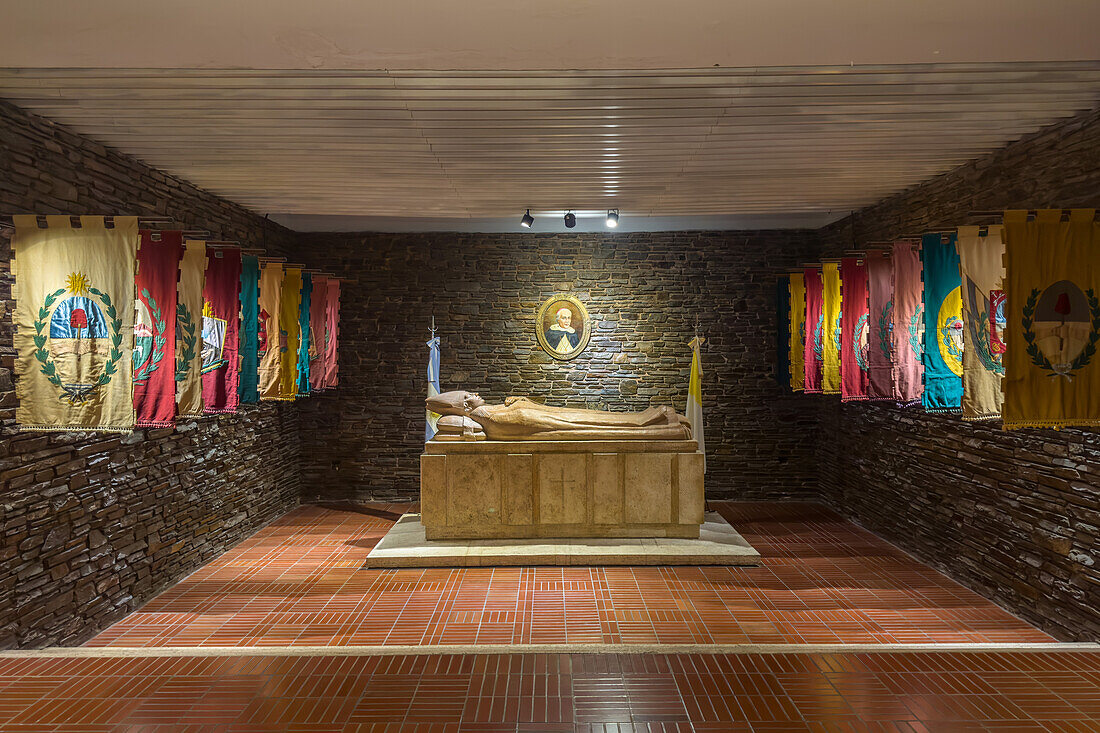 Das Grab von Bischof Justo de Santa María de Oro y Albarracín in der Krypta der San Juan de Cuyo Kathedrale in San Juan, Argentinien. Er war der erste Bischof von San Juan und ein Unterzeichner der argentinischen Unabhängigkeitserklärung von Spanien. Das Grabmal wird von den Flaggen der 19 Departements der Provinz San Juan flankiert.