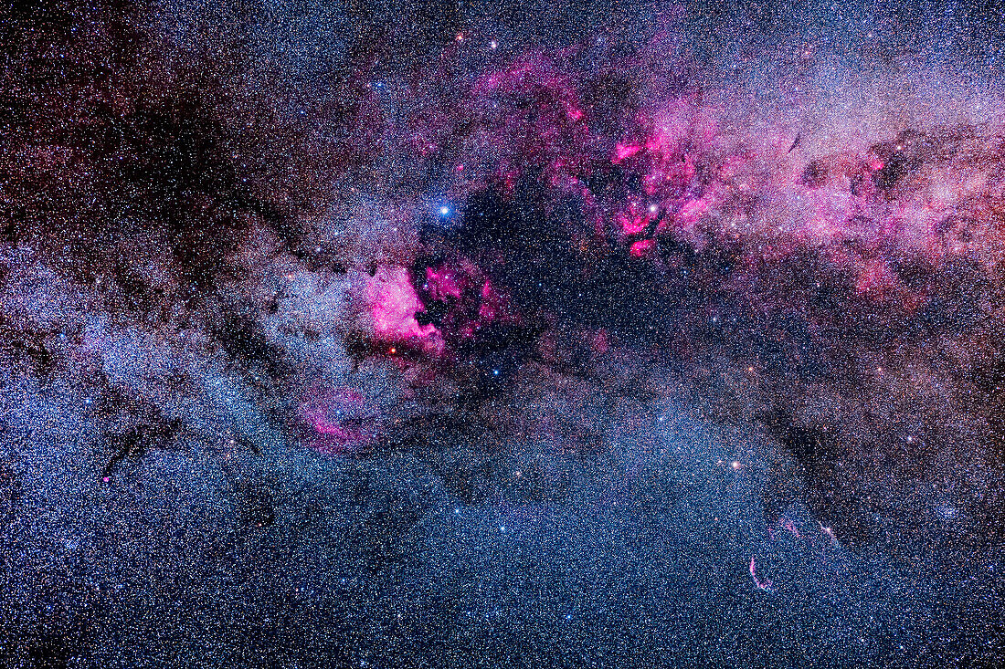 A framing of the major areas of bright and dark nebulosity in Cygnus, showing pink emission nebulas contrasting with dark dusty regions in the Cygnus arm of the Milky Way. The main area of the bright Cygnus Starcloud is at upper right.