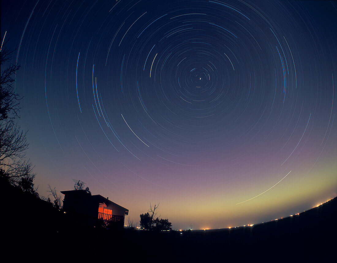 Circumpolar Star Trails -- Pentax 6x7 Kamera mit 35mm Vollformat Fischaugenobjektiv bei f/5.6. Fujichrome 100F Diafilm und 2 Stunden Belichtung. Aufgenommen von zu Hause aus im Juli 2004. Die Aurora verleiht dem Himmel Farbe.