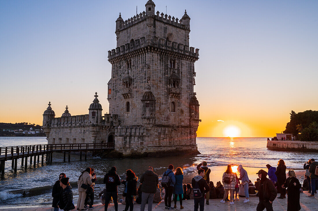 People enjoy a beautiful sunset from Belem Tower or Tower of St Vincent on the bank of the Tagus River, Lisbon, Portugal