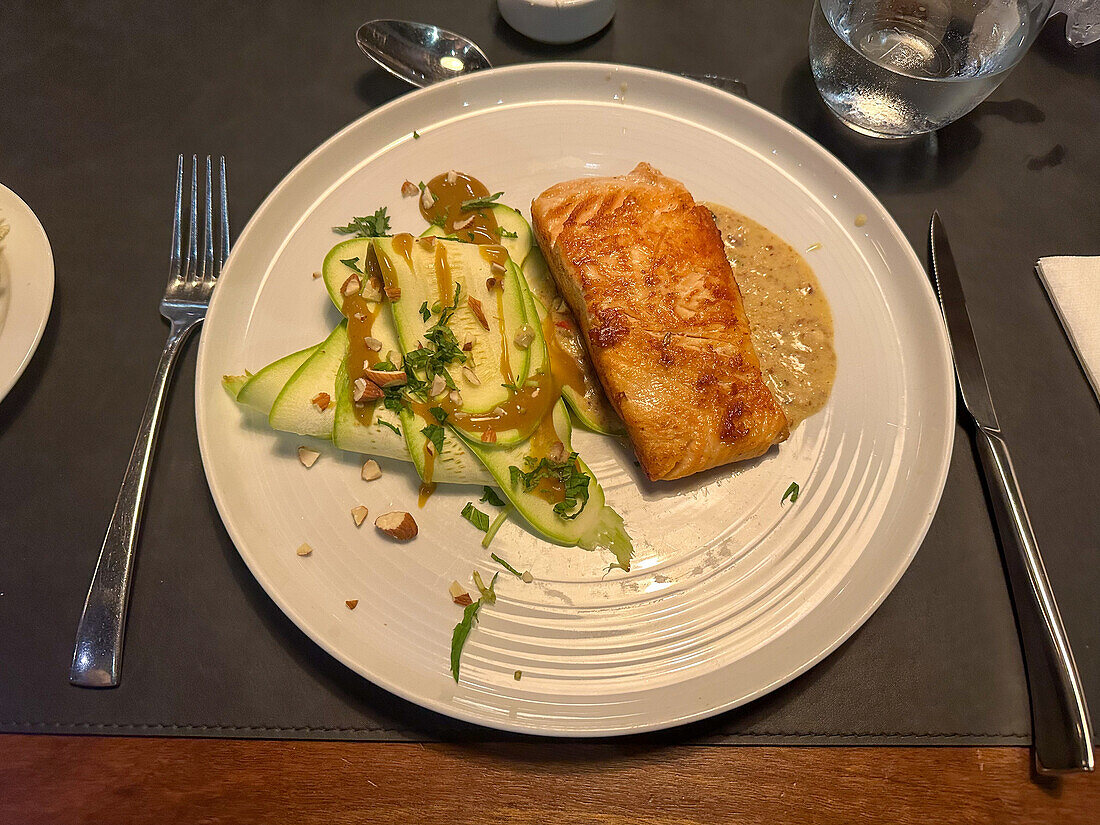 Lachs mit einer Mandelsauce und Zucchini mit einer Honig-Senf-Sauce in einem Restaurant in San Rafael, Argentinien.