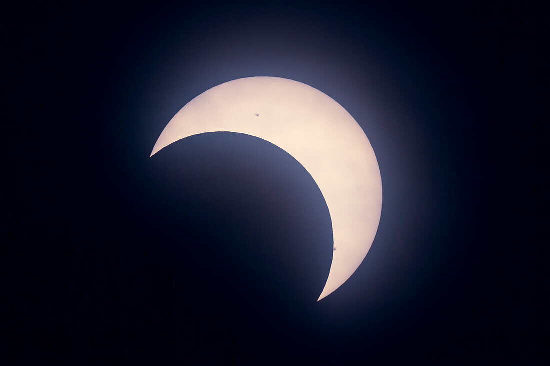 The partial solar eclipse as seen from Calgary, Alberta, on May 20, 2012, but seen as an annular eclipse from the SW United States. This was taken at maximum eclipse at 7:14 pm MDT, with 62% of the Sun covered. Taken from the TELUS Spark science centre at a public event there, and taken with an 80mm A&M apo refractor at f/6 (480mm focal length) and Canon 60Da camera at ISO 100 and 1/250 second exposure through a Baader solar filter. The Sun was in high cloud and not in a clear blue sky.