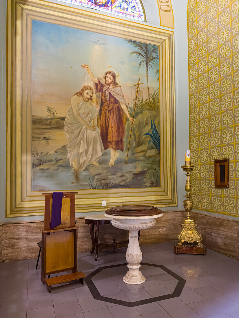 The baptistry in a side chapel of the ornate Cathedral of the Immaculate Conception in San Luis, Argentina. A painting depicts the baptism of Jesus by John the Baptist.