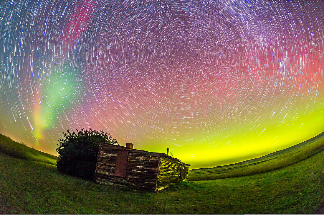 Ein zirkumpolares Sternspurkomposit, aufgenommen an der alten Larson Ranch im Frenchman Valley im Grasslands National Park, Saskatchewan, am 27. und 28. August 2014. Die Pionierhütte war das Zuhause des legendären Westernautors und Filmstars Will James, der als Ernest Dufault in Quebec geboren wurde. Er lebte in dieser Hütte, als er auf den Ranches in der Gegend arbeitete. Die Aurora war in dieser Nacht ausgezeichnet. Dies ist ein Stapel von 20 1-Minuten-Belichtungen bei ISO 2500 mit dem 15-mm-Vollformat-Fischaugenobjektiv bei f/3,2 und der Canon 6D. Der Vordergrund und die punktförmigen Stern