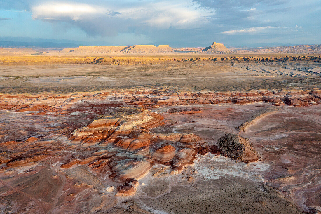 Luftaufnahme des ersten Lichts auf Factory Butte mit den farbenfrohen Bentonite Hills im Vordergrund, nahe Hanksville, Utah.