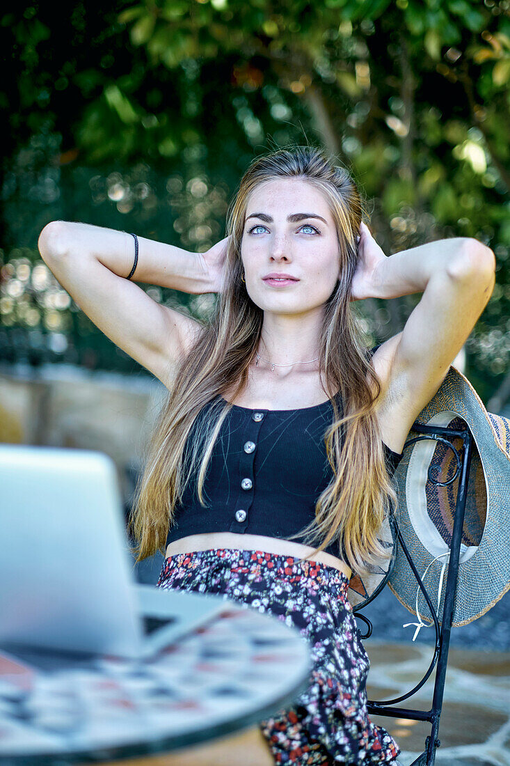 Portrait of a young caucasian woman posing outdoor in a garden with a laptop looking for information in internet. Lifestyle concept.