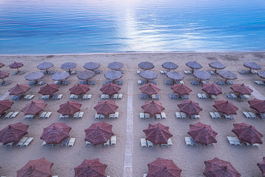 Luftaufnahme einer großen Gruppe von aufgeräumten Sonnenschirmen am Mittelmeer, Italien, Europa